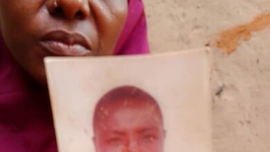 Woman holding a worn photograph partially covering her face.