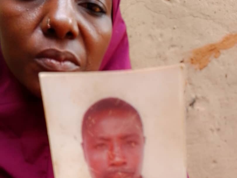 Woman holding a worn photograph partially covering her face.