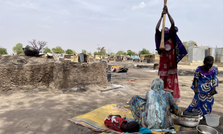 People amidst a makeshift environment with basic belongings, indicating a scene of daily life in a resource-scarce setting.