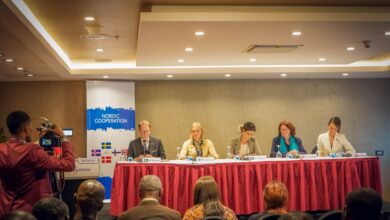 Panel of five individuals at a Nordic Cooperation conference with an audience and a cameraman in the foreground.