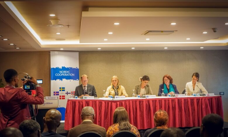 Panel of five individuals at a Nordic Cooperation conference with an audience and a cameraman in the foreground.