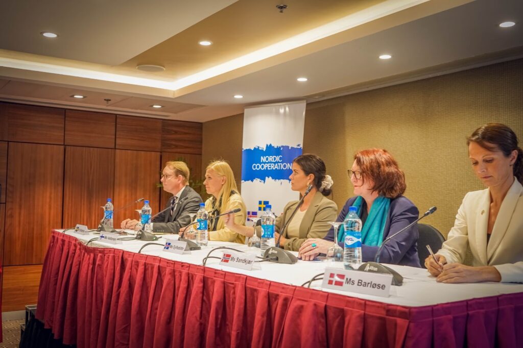 Panelists at a Nordic Cooperation event seated at a conference table with microphones and name tags.