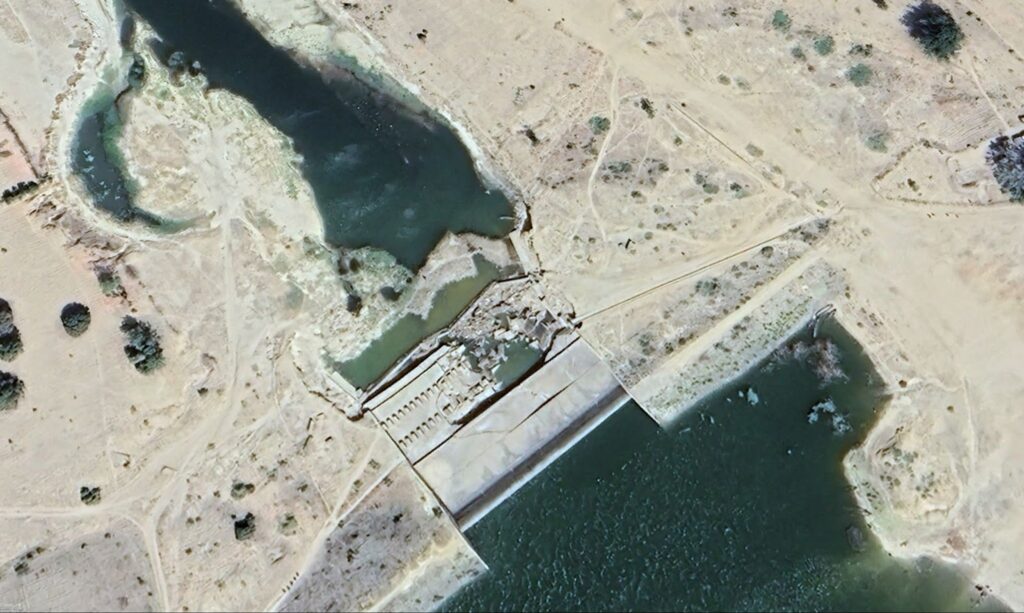 Aerial view of a dam on a river with surrounding arid landscape.