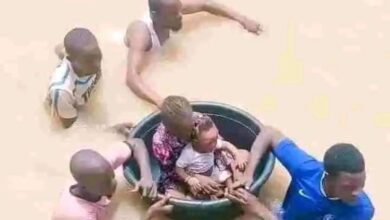 People using a large basin to float through a flood, aiding others in the water.