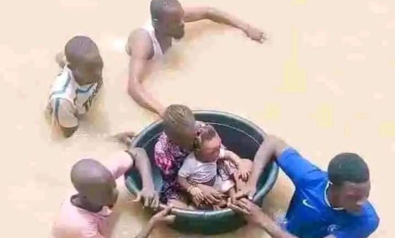 People using a large basin to float through a flood, aiding others in the water.