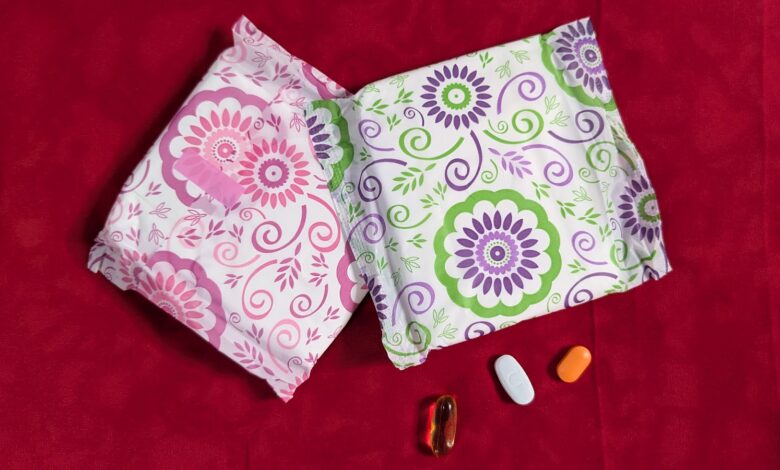 Two patterned tissue packages and three pills on a red background.