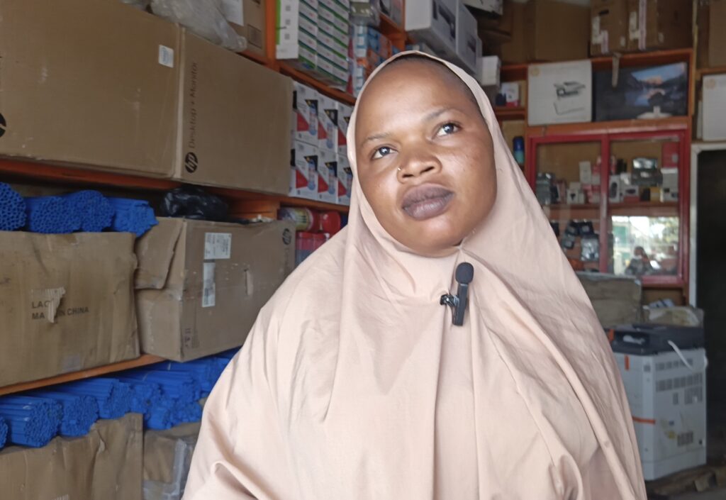 Woman in a beige hijab with a headset in a storage room.