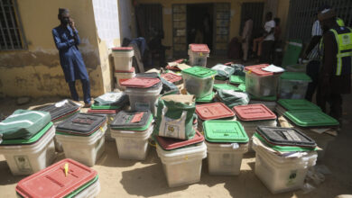 Election officials and stacked ballot boxes at a polling station.