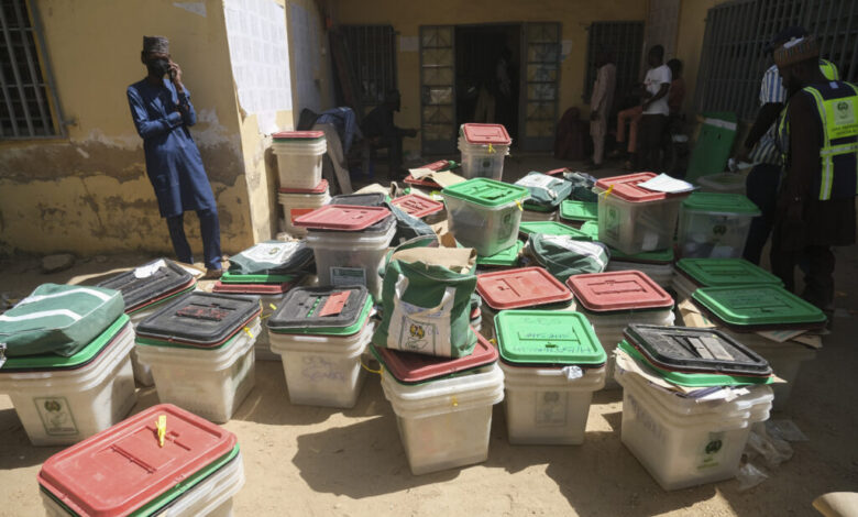 Election officials and stacked ballot boxes at a polling station.