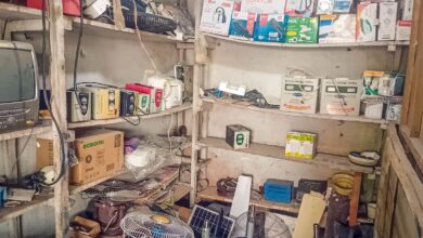 An overcrowded storage room with various electronic items and boxes on shelves.