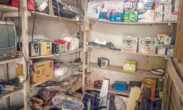 An overcrowded storage room with various electronic items and boxes on shelves.