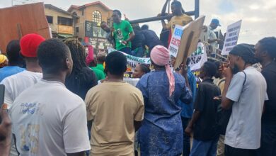 Protesters with signs demanding changes, rallying on a street.