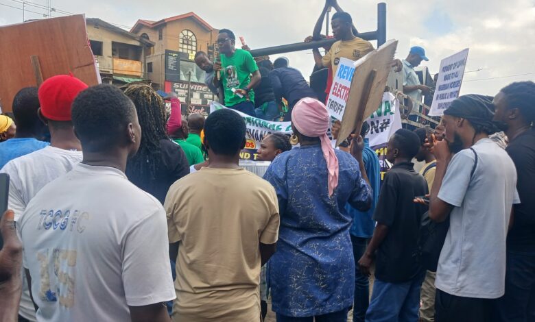 Protesters with signs demanding changes, rallying on a street.