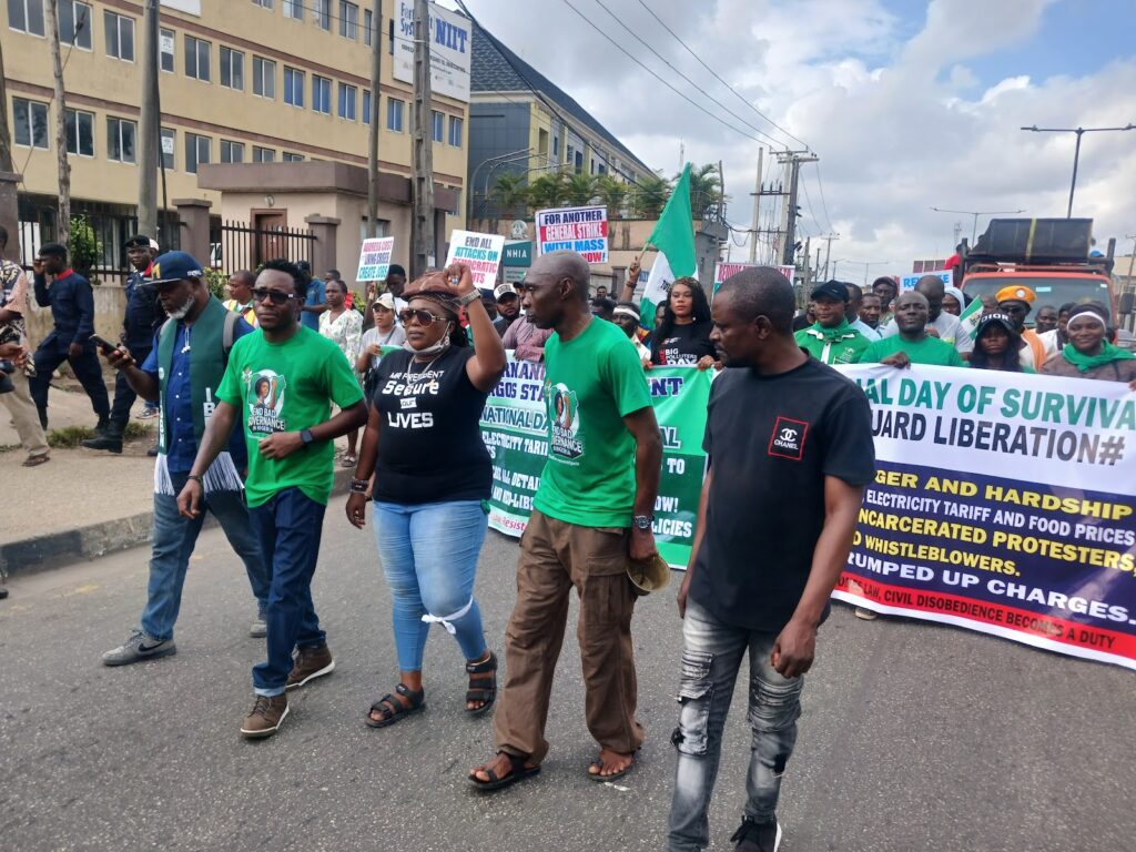 Group of people marching in protest with banners and signs on a city street.