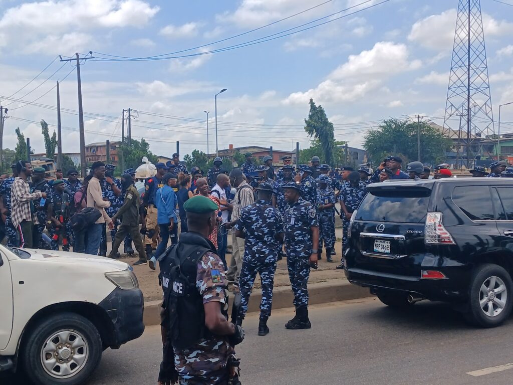 A group of police officers in uniform gathered on a city street, with people and vehicles around them.