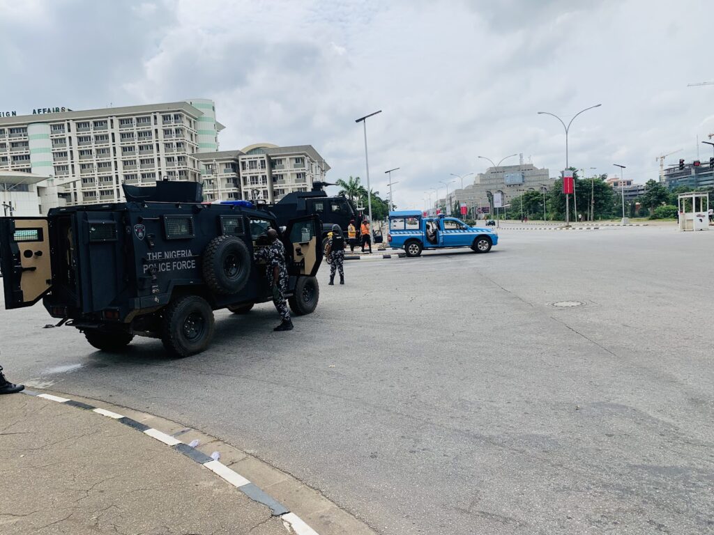 Nigerian police force armored vehicles and officers on a city street.