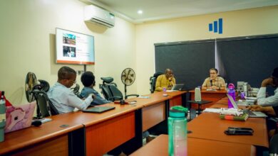 Professionals in a meeting room with a presentation on the screen.