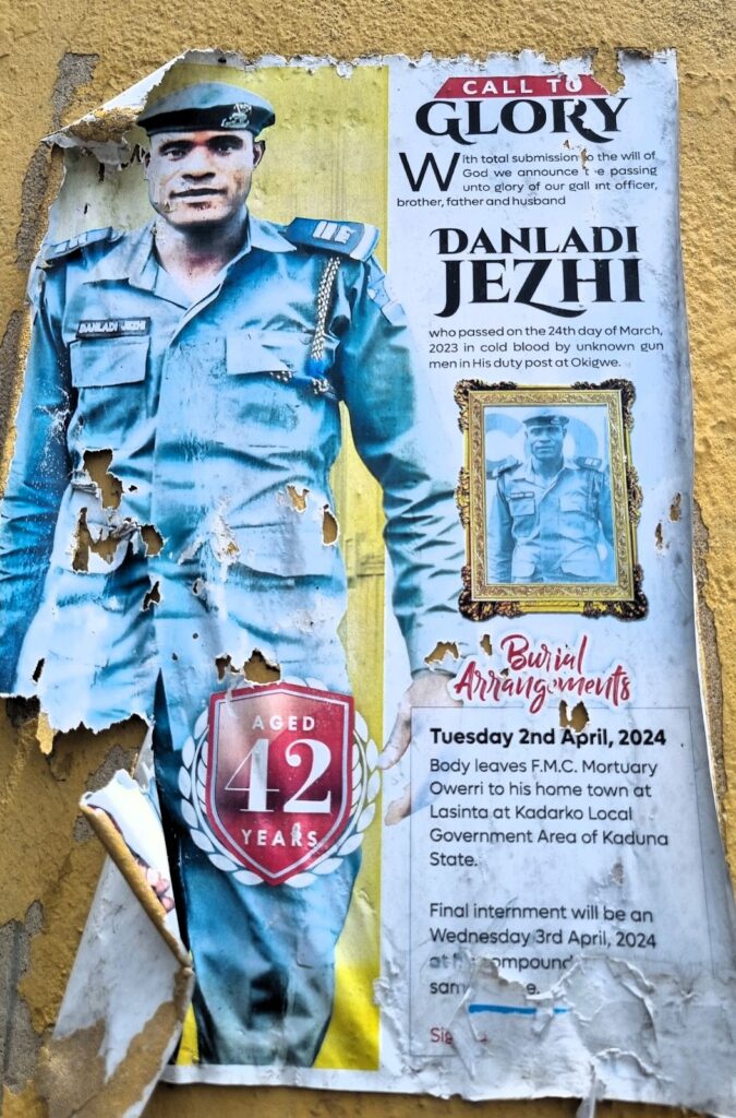 Torn obituary poster on a wall with a photo of a uniformed man, text for funeral arrangements, and inscription "Aged 42 years."