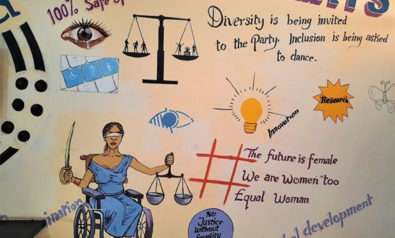 Wall mural with symbols of diversity, inclusion, and female empowerment, including Justice Lady in a wheelchair.