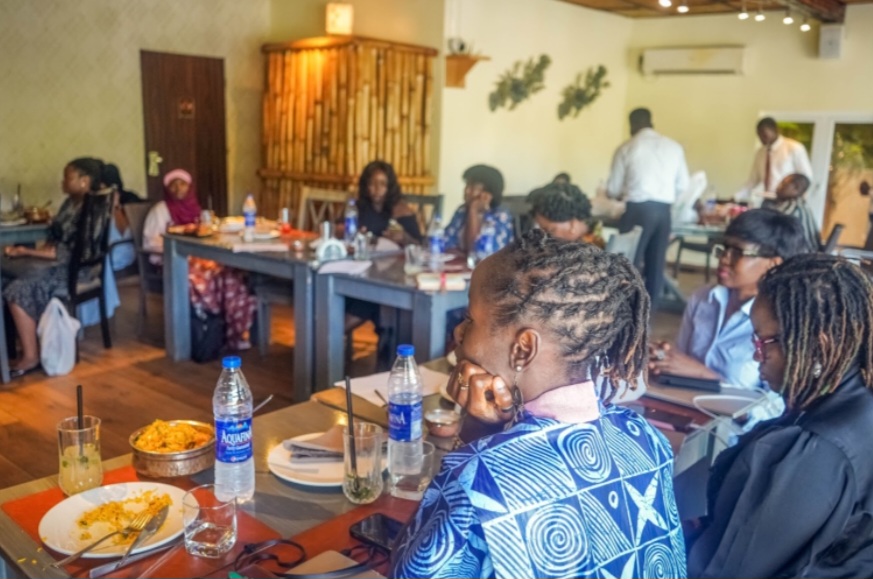 People attending a meeting or workshop in a restaurant setting with plates and bottles of water on the tables.