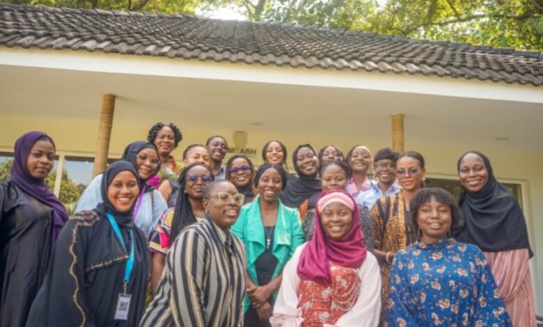 A diverse group of smiling women gathered for a group photo outdoors.