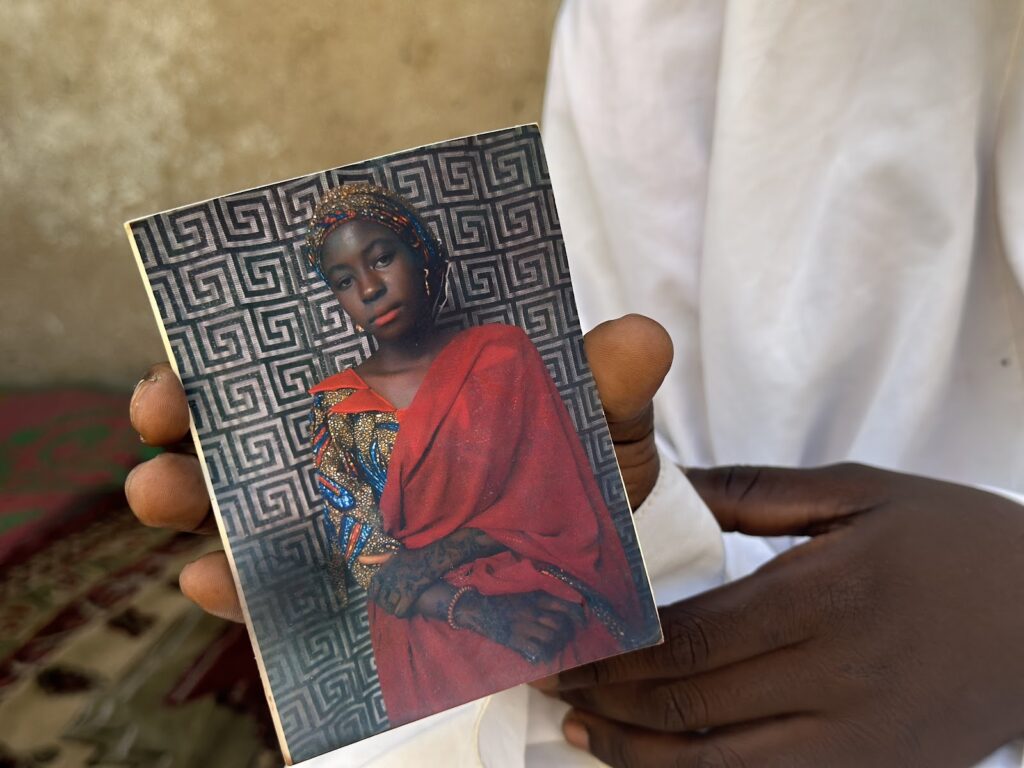 Person holding a photo of a woman in traditional attire.