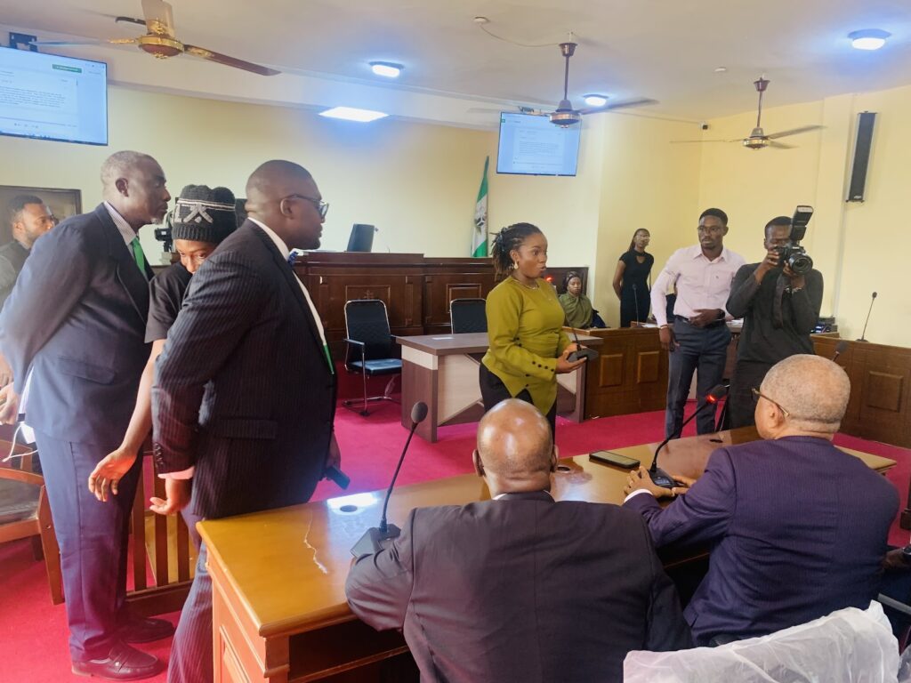 Professionals and a photographer in a courtroom during a proceeding.