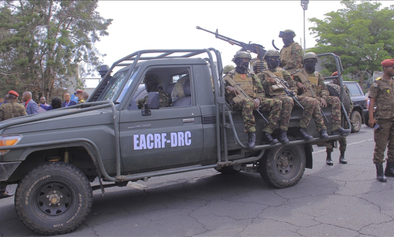 A military vehicle with soldiers onboard and others standing beside, labeled "EACRF-DRC."