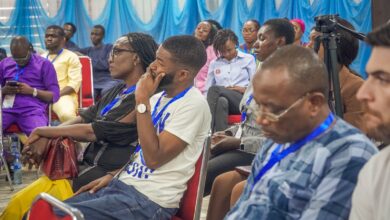 Audience members seated at an event with blue and white decor, focused on the presentation.