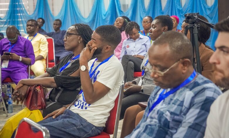 Audience members seated at an event with blue and white decor, focused on the presentation.