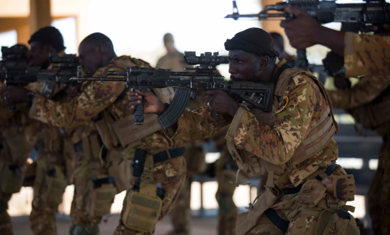 A group of soldiers in camouflage gear aiming their rifles during a training exercise.