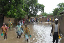 Residents walking through a flooded village street.