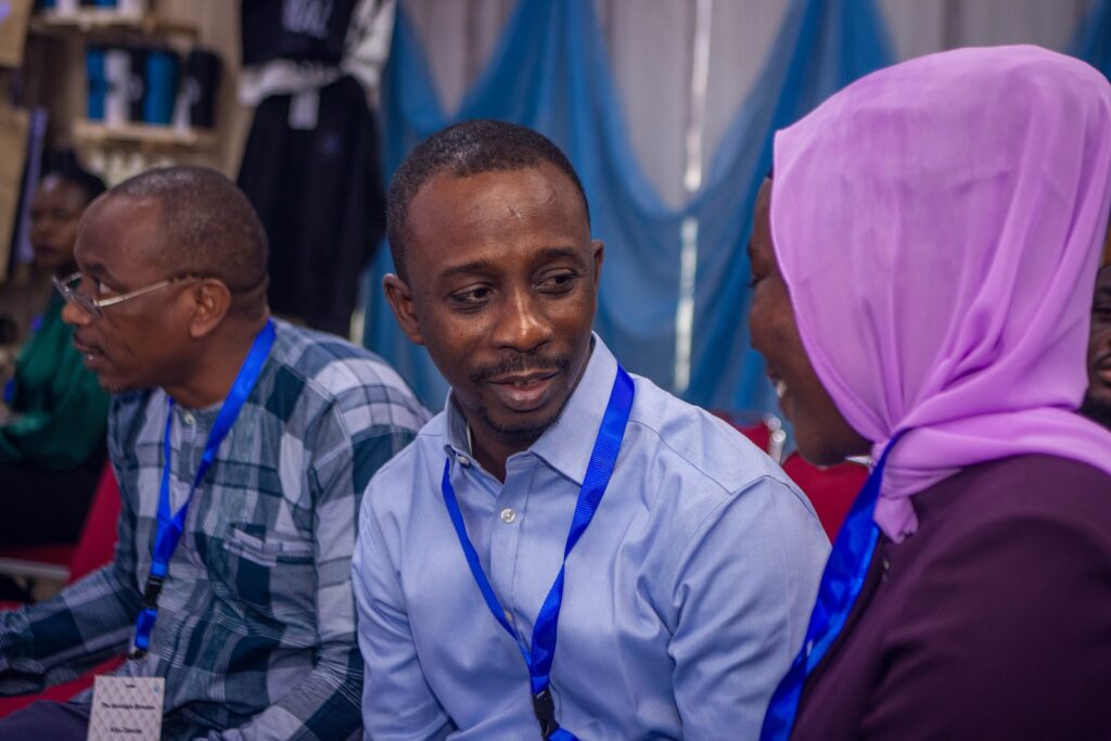 Attendees with lanyards in a conversation at an event.