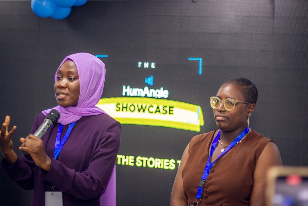 Two women presenting at the HumAngle Showcase event, one speaking with a microphone.