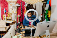 Person podcasting in a richly decorated room with eclectic decor and a ring light.