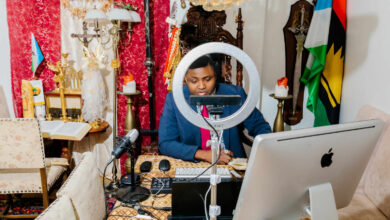 Person podcasting in a richly decorated room with eclectic decor and a ring light.