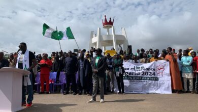 A group of people at a protest with banners advocating against bad governance in Nigeria.