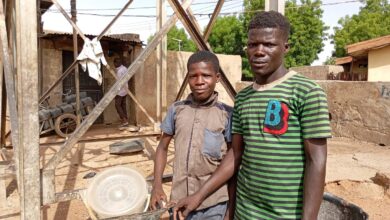 Ibrahim and Isma’il pose for a picture at their place of labour with their disc mill grinder at Kuka, Tsohuwar Kasuwa, Potiskum.