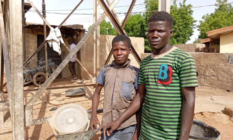 Ibrahim and Isma’il pose for a picture at their place of labour with their disc mill grinder at Kuka, Tsohuwar Kasuwa, Potiskum.