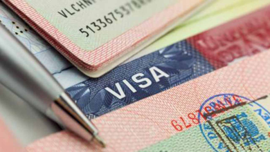 Close-up of a passport with a visa stamp and a pen resting on top.