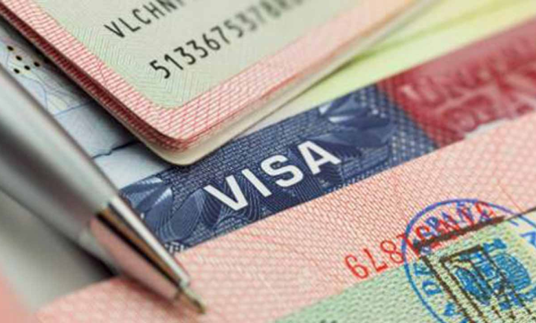 Close-up of a passport with a visa stamp and a pen resting on top.