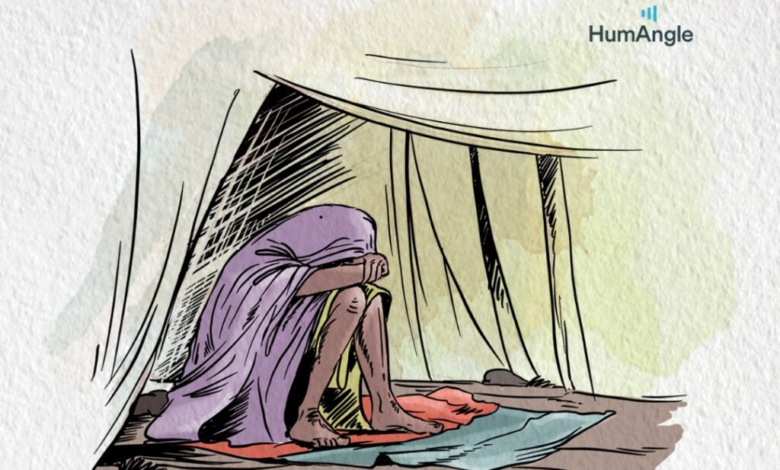 A person sits wrapped in a cloth inside a tent, with their head resting on their knees, conveying a sense of solitude and contemplation.