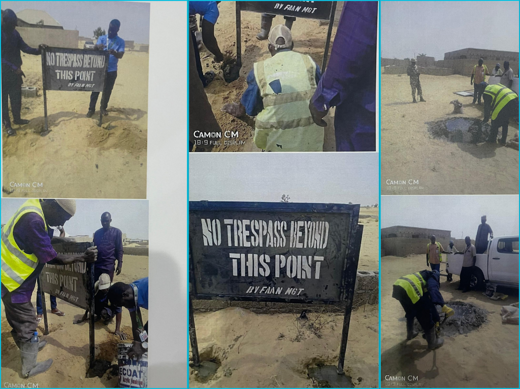 Workers install "No Trespass Beyond This Point" signs in a sandy area, working with tools near a truck and concrete mixture.