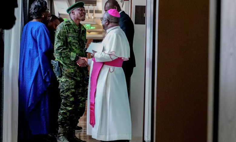 A soldier and a religious leader in conversation, surrounded by others, in a hallway.