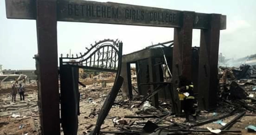 Damaged entrance of Bethlehem Girls' College after a disaster, with debris and rubble scattered around.