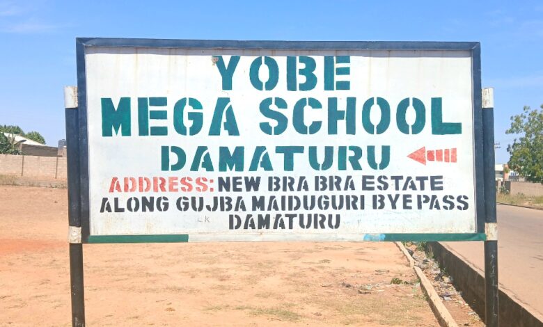 Sign for Yobe Mega School, Damaturu, with address: New Bra Bra Estate, along Gujba Maiduguri Bypass, Damaturu, under a clear sky.