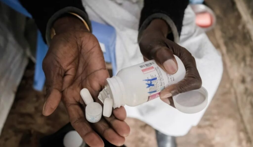 A person holding a bottle of pills in one hand, with pills poured into the other hand.