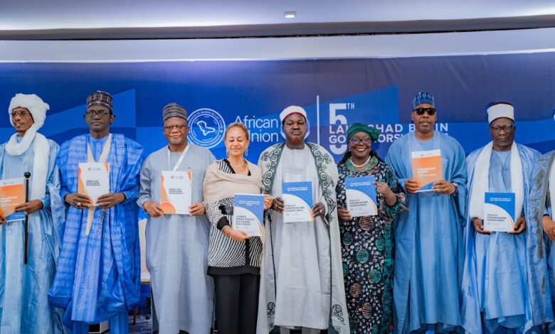 A group of individuals stands holding policy documents at the 5th Lake Chad Basin Governors Forum, African Union backdrop visible.