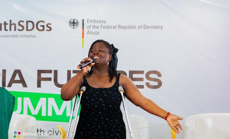 Person using crutches speaks into a microphone at a podium with NG Youth SDGs and German Embassy logos in the background.