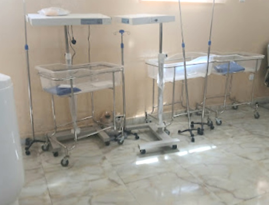 Three empty hospital bassinets with overhead lamps in a sterile room.